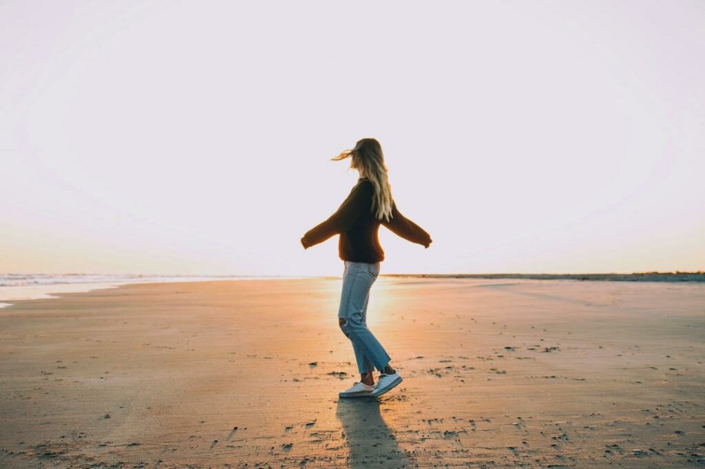 Femme debout sur le sable près du bord de mer pendant l'heure dorée